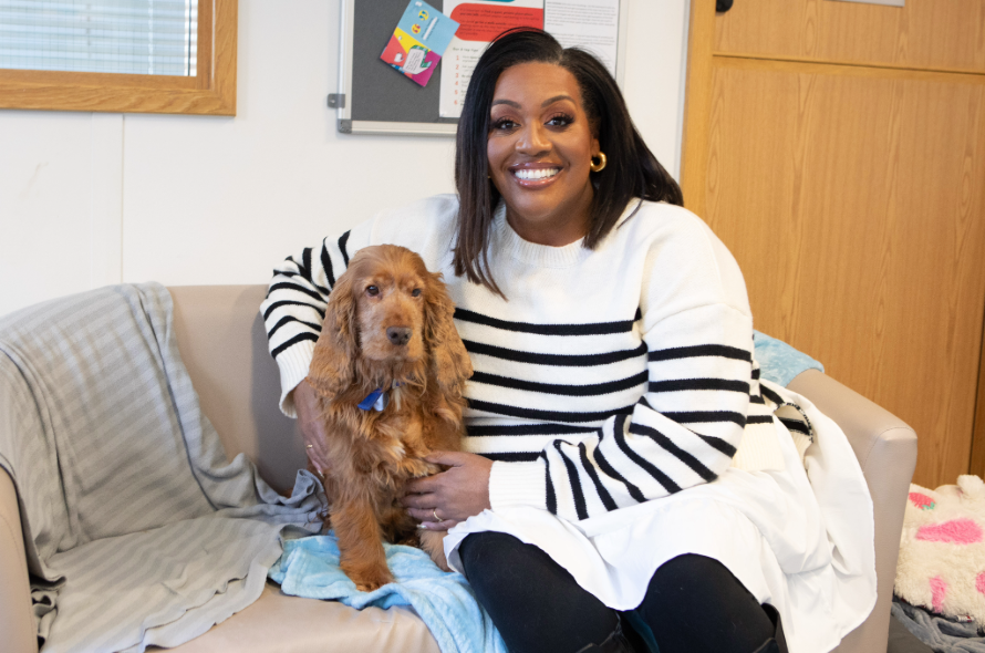 TV presenter sitting on a sofa with a cocker spaniel 