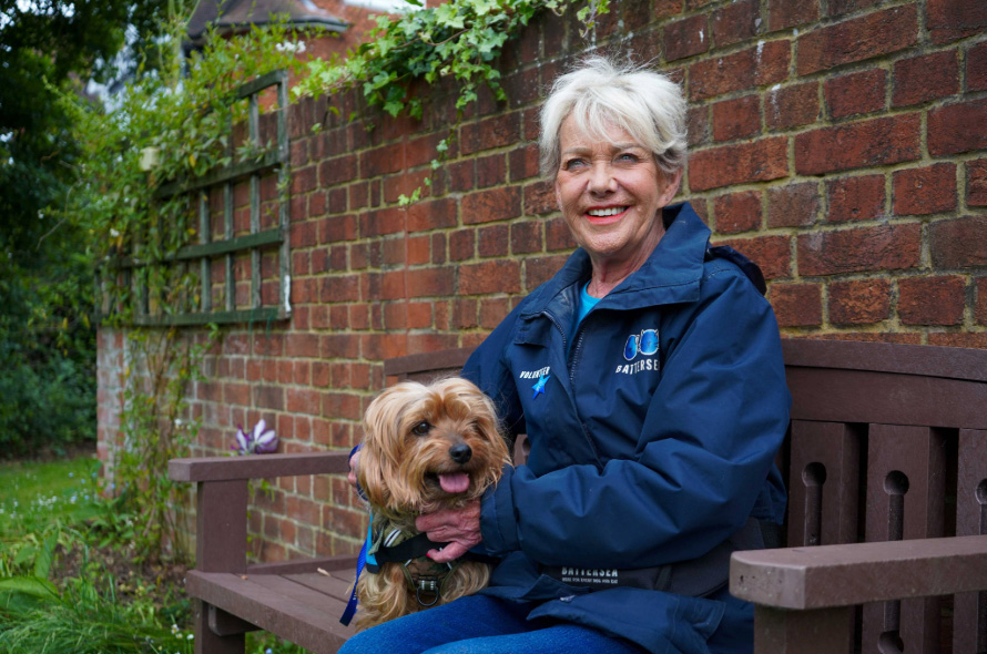 Ann Palmer Battersea volunteer sitting on bench with dog