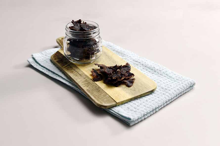 Beef jerky in a glass jar on a chopping board