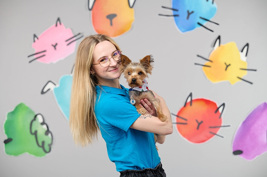 Battersea staff member holding a Yorkshire Terrier smiling at the camera