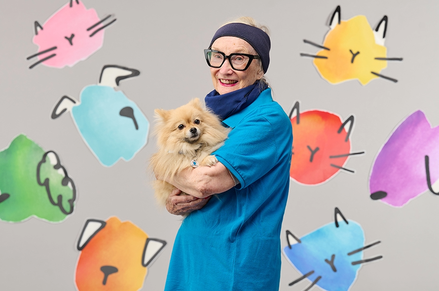 Battersea staff member standing holding a Pomeranian in her arms