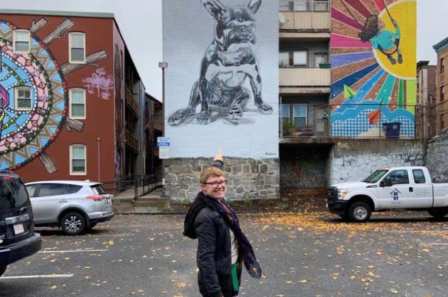 Person pointing at a mural of a French Bulldog