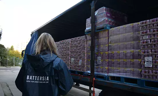 Battersea staff member looking at a large truck of pet food