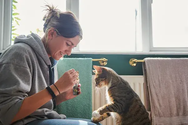 Woman and her cat looking at a bottle 